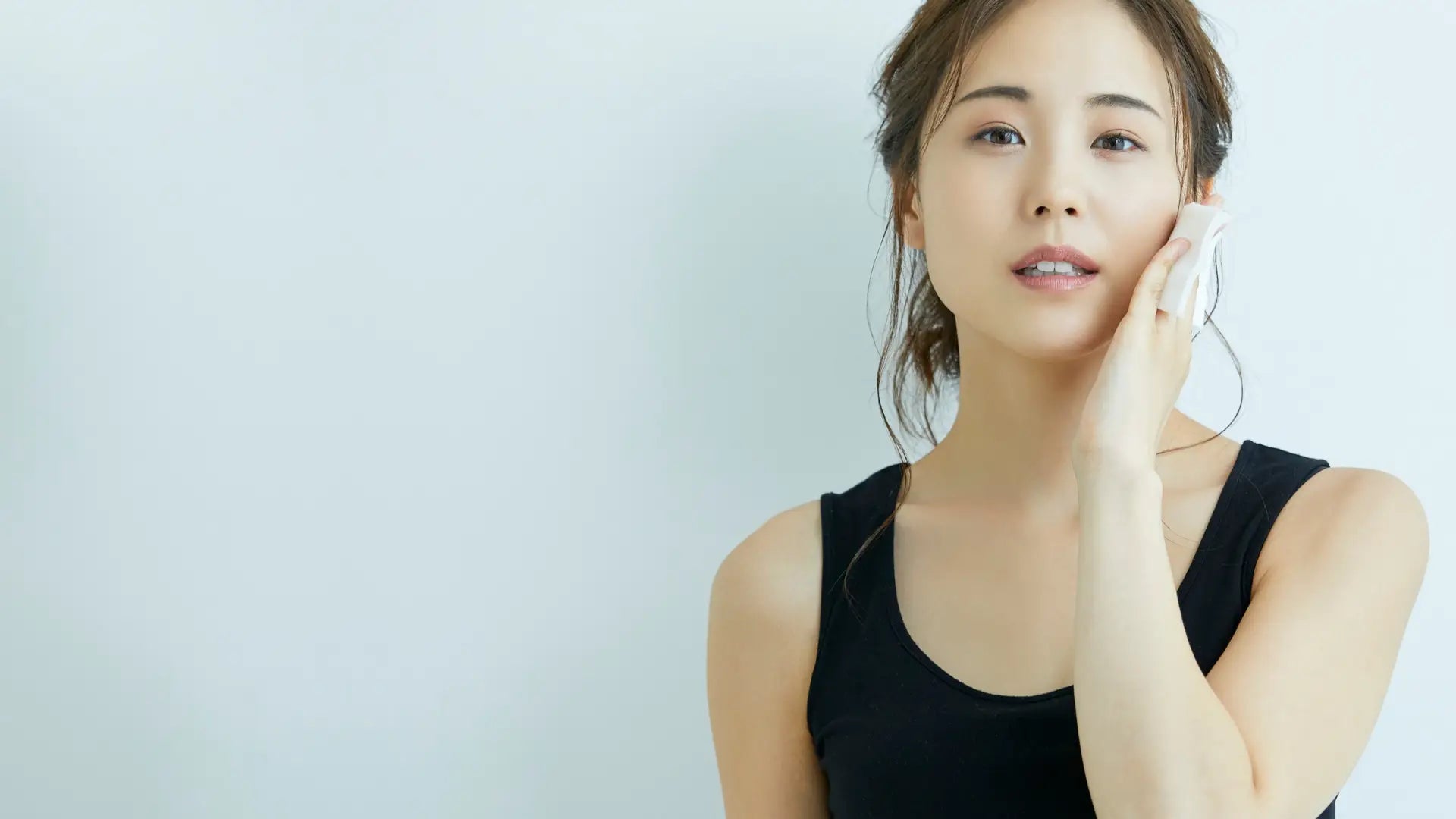 Woman in a black sleeveless top against a light gray background