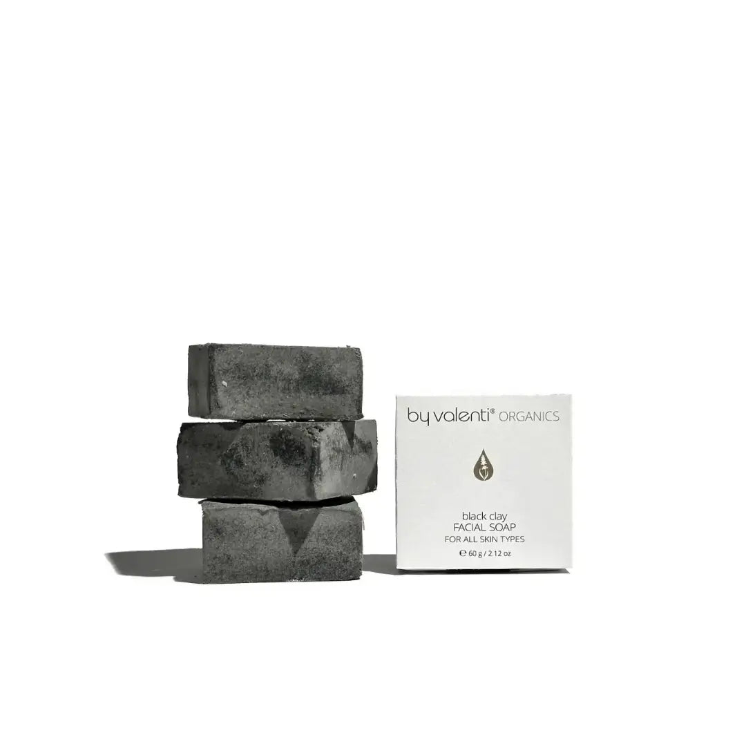Stack of By Valenti black charcoal soap bars with a box labeled 'by valenti organics' on a white background
