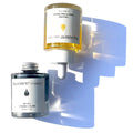 Two By Valenti skincare products, Olio di C 10% Vitamin C Elixir and Bakuchiol Smoothing Serum, with white and yellow liquid inside them, placed on a surface with a shadow falling across the scene.