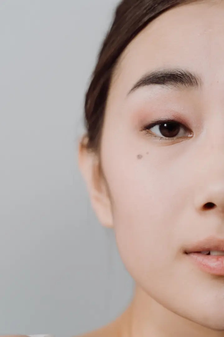 Close-up of an Asian woman's face with a neutral expression on a gray background